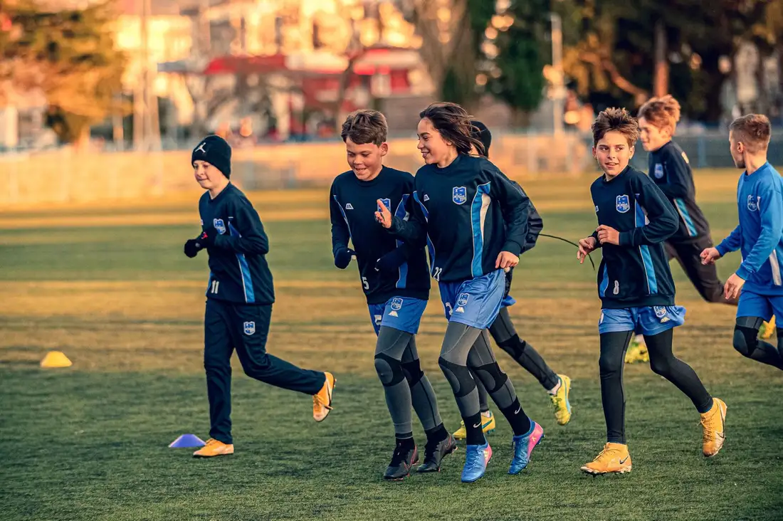 Young athletes running cone drills at a football training session in the morning light.