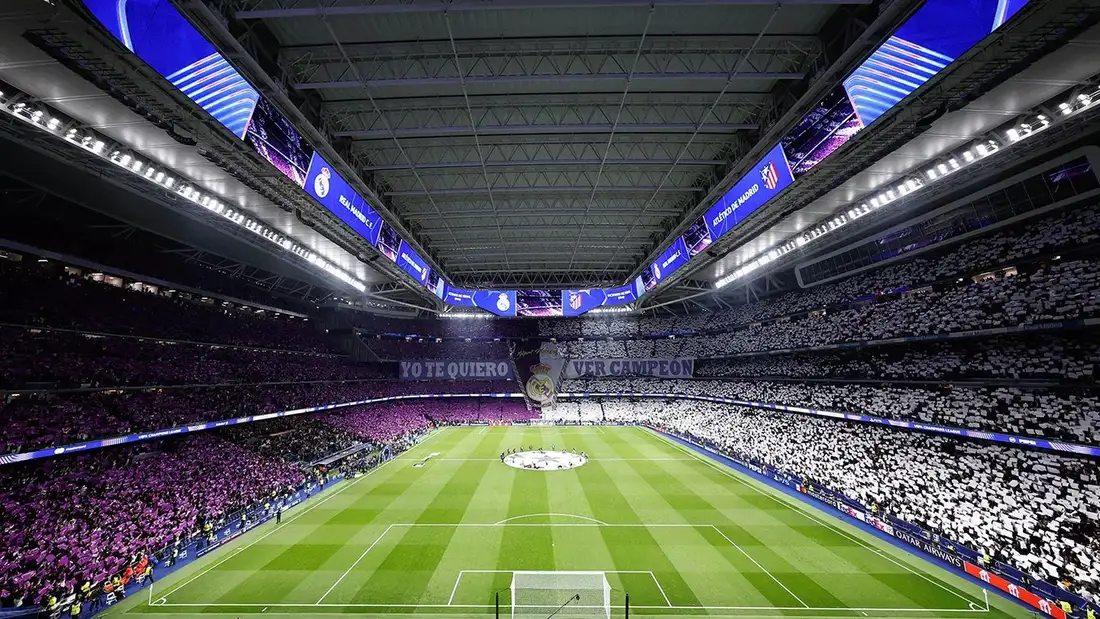 The sweeping tiered stands of a grand football stadium at dusk.